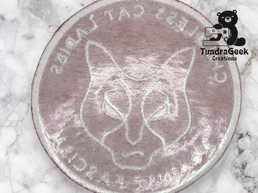 Round embroidered patch featuring an outlined cat face and the text “CLAWLESS CAT LADIES AGAINST RASCAL” on a light marbled background. TundraGeek Creations logo in the top right corner.
