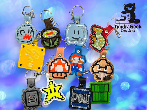 A collection of keychains featuring pixel art designs inspired by classic Mario game characters and items, displayed on a blue bokeh background with the TundraGeek Creations logo.