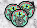 Three round embroidered patches with a goat head, two yellow crescent moons, an inverted cross, and the text TODAY IS GONNA BE MY DAY on a teal background.