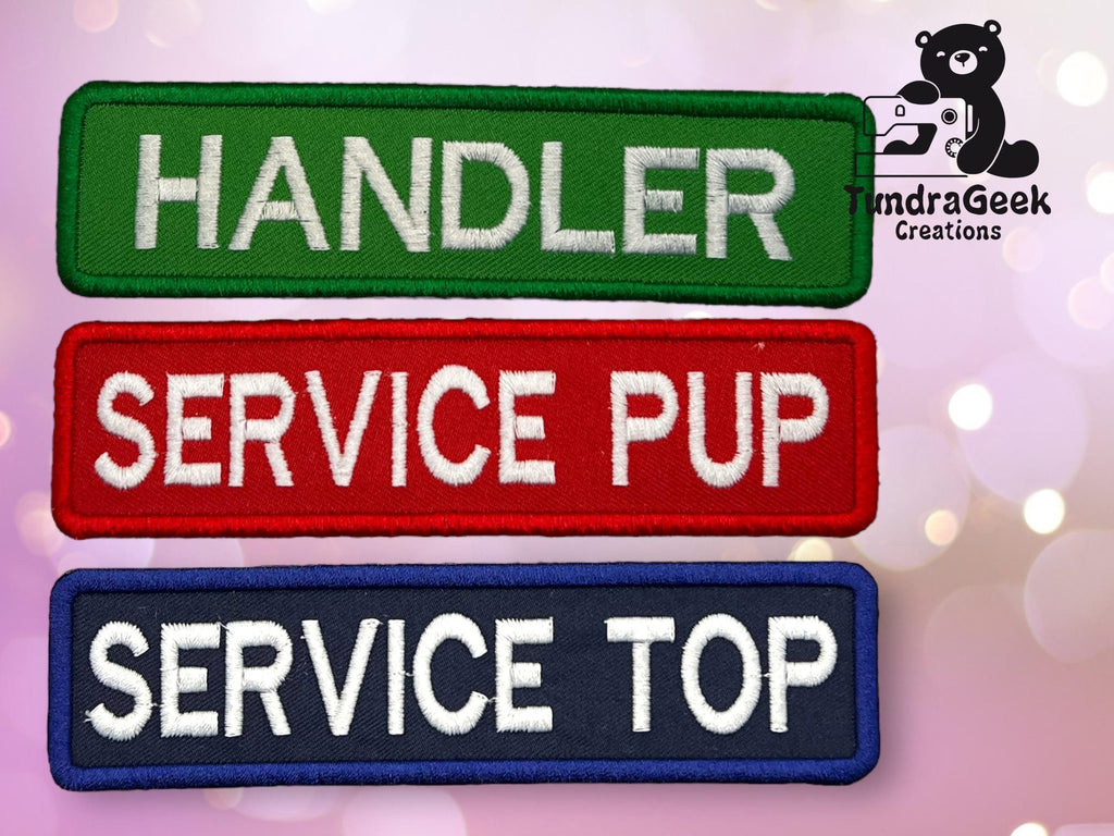 Three rectangular fabric patches labeled Handler (green), Service Pup (red), and Service Top (blue) on a pink background, with the TundraGeek Creations logo in the corner.