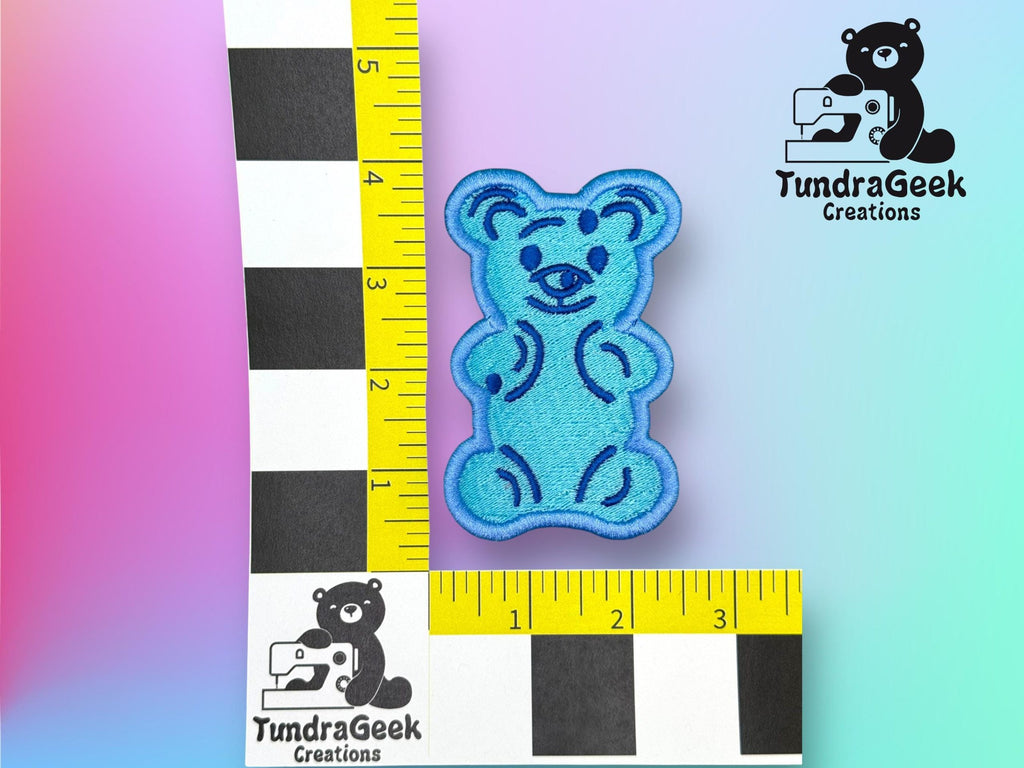 A blue, bear-shaped patch is shown next to a ruler, measuring approximately 2.5 inches tall. TundraGeek Creations logo appears in two corners.