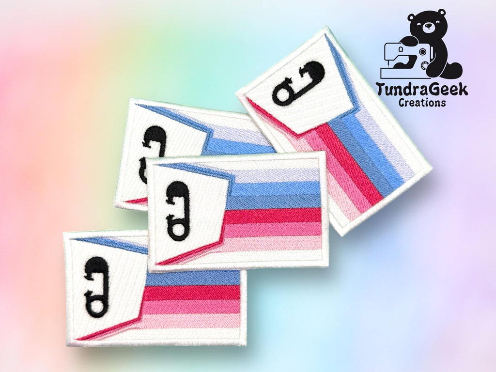 Four rectangular patches with the polyamory pride flag colors and a black pi symbol, displayed on a pastel gradient background with the TundraGeek Creations logo in the corner.
