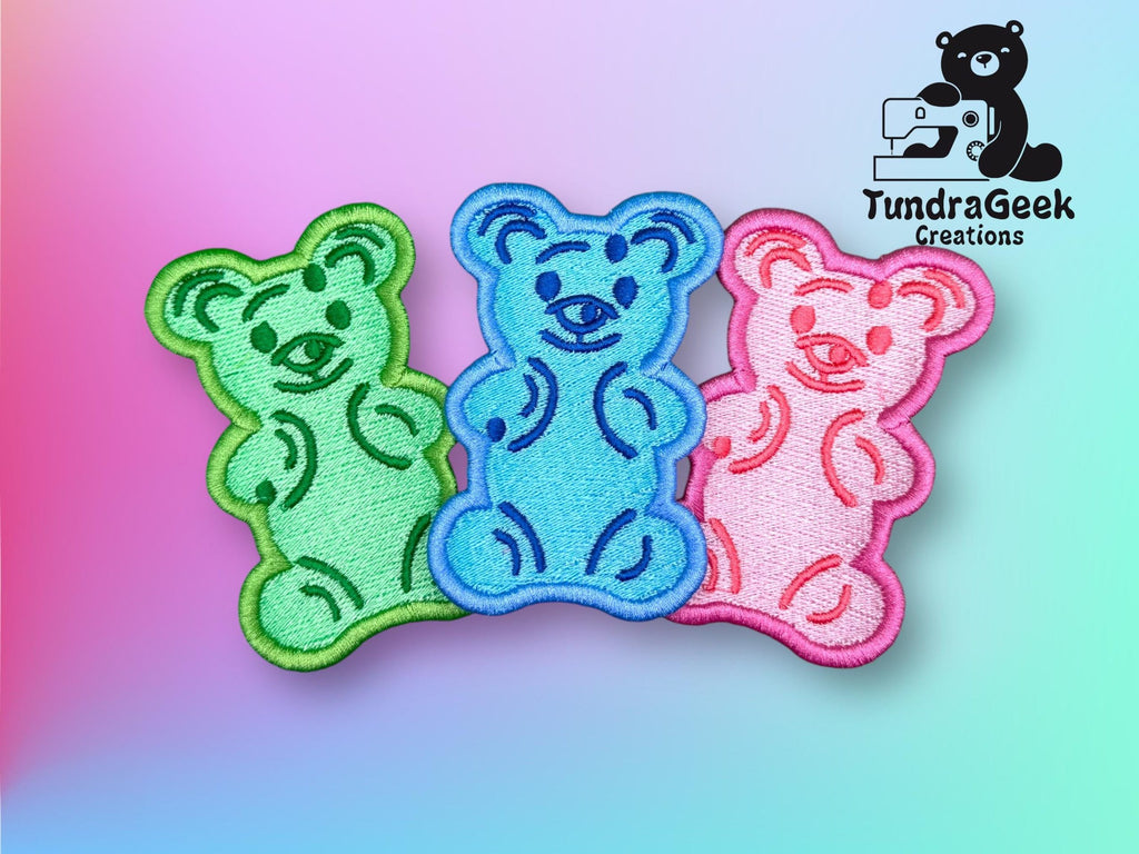 Three embroidered bear patches in green, blue, and pink are displayed on a pastel gradient background. A “TundraGeek Creations” logo appears in the top right corner.
