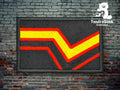 A rectangular patch with a zigzag red, yellow, and orange stripe on a black background, displayed against a brick wall with the TundraGeek Creations logo in the top right corner.