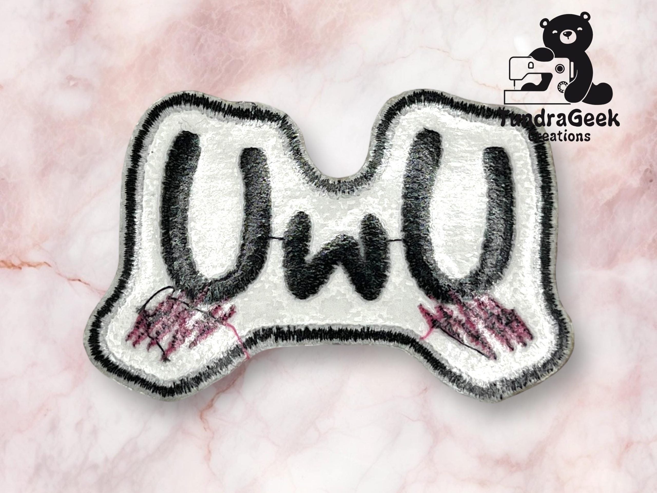 Embroidered patch with UWU text, featuring black letters and pink blushing marks, on a light pink marble background with an IndraGeek Creations logo in the corner.