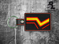 A rectangular fabric keychain with red and yellow chevron embroidery on a black background, attached to a metal key ring. The Tundra Geek Creations logo appears in the corner.
