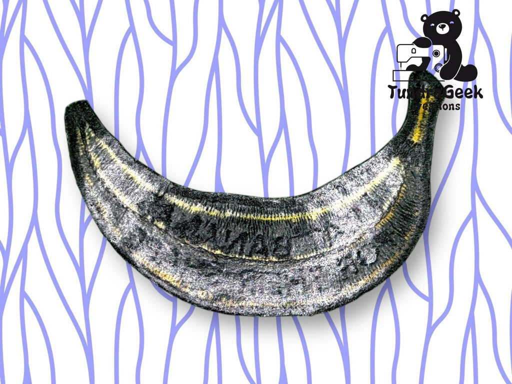 A metallic, crescent-shaped object resembling a banana on a white background with blue wavy lines and a cartoon bear logo in the corner.
