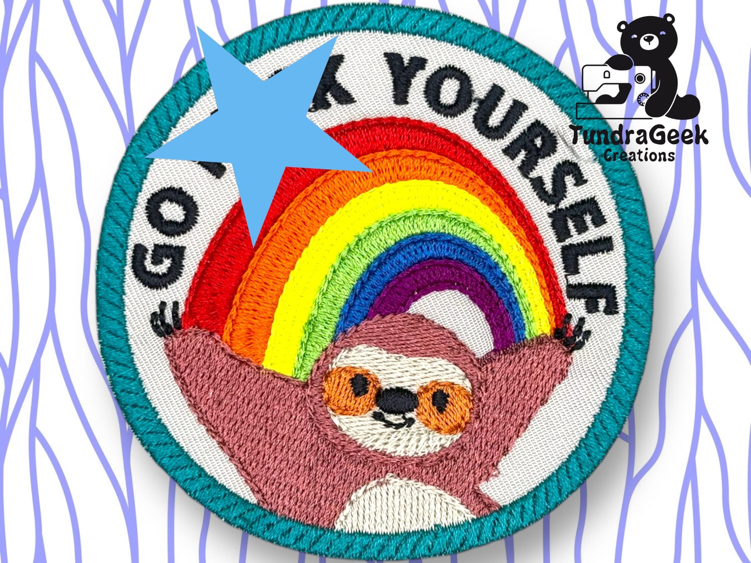 A circular embroidered patch features a smiling sloth with arms raised under a rainbow, with the text “GO F*** YOURSELF” partially obscured by a blue star. TundraGeek Creations logo in corner.