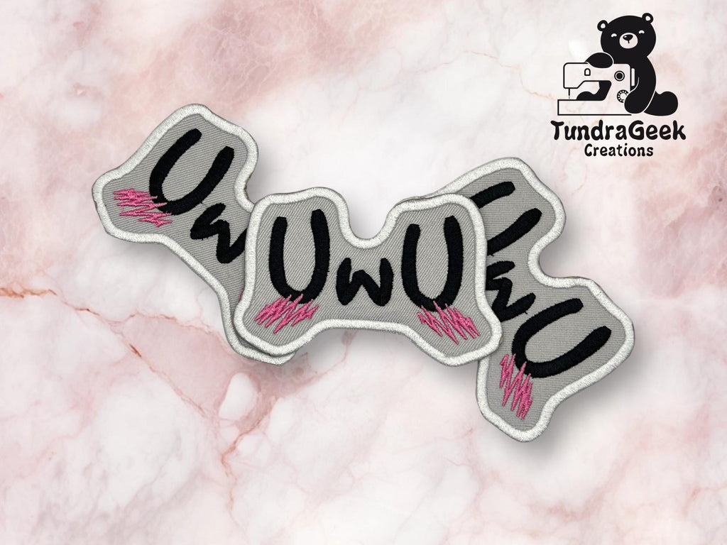 A fabric patch with the text UwU in black font and pink blush marks, displayed on a marble background with the TundraGeek Creations logo in the upper right corner.