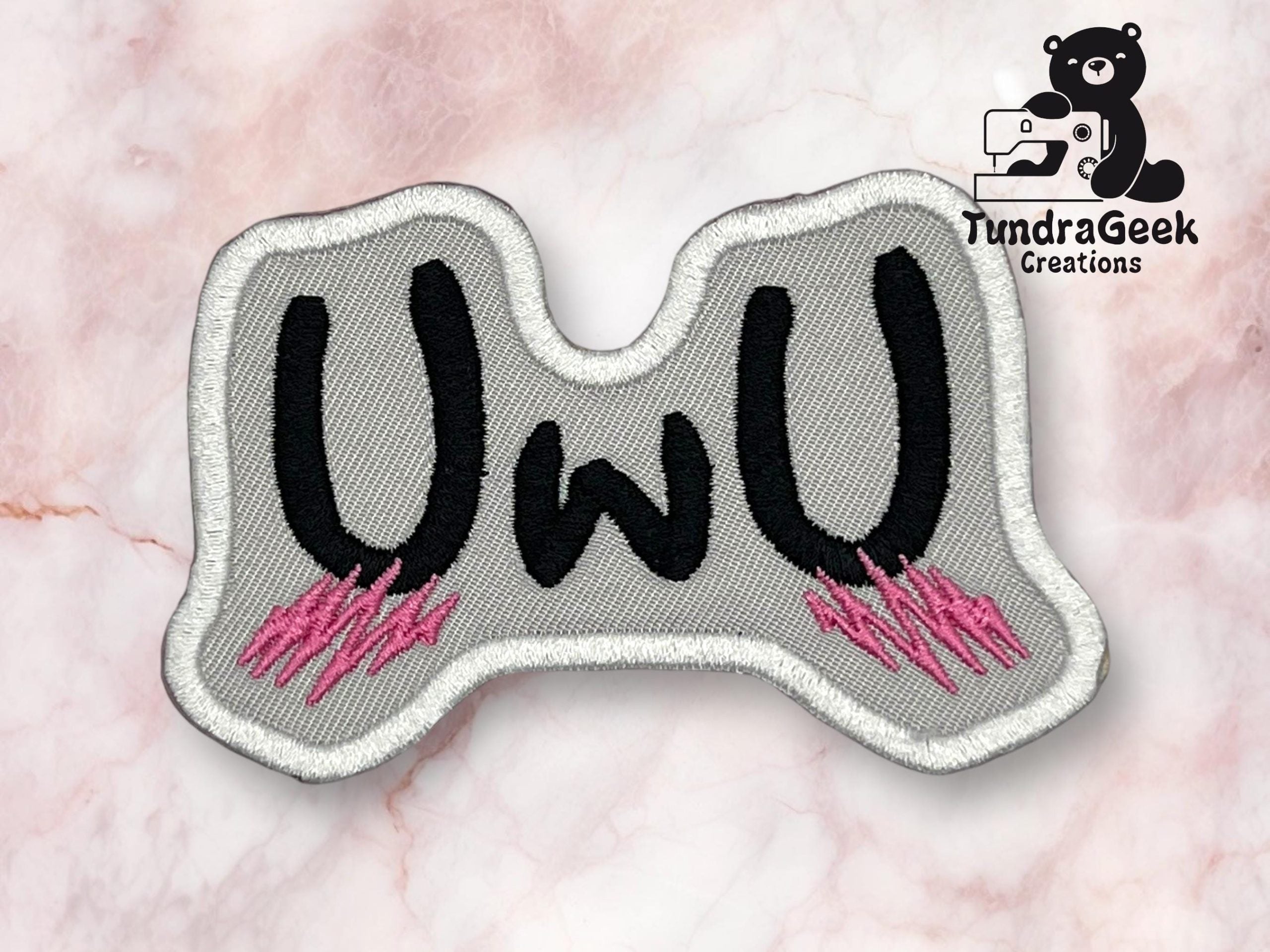 A gray embroidered patch with black UwU text and pink accents, set against a light marble background with the TundraGeek Creations logo in the top right corner.