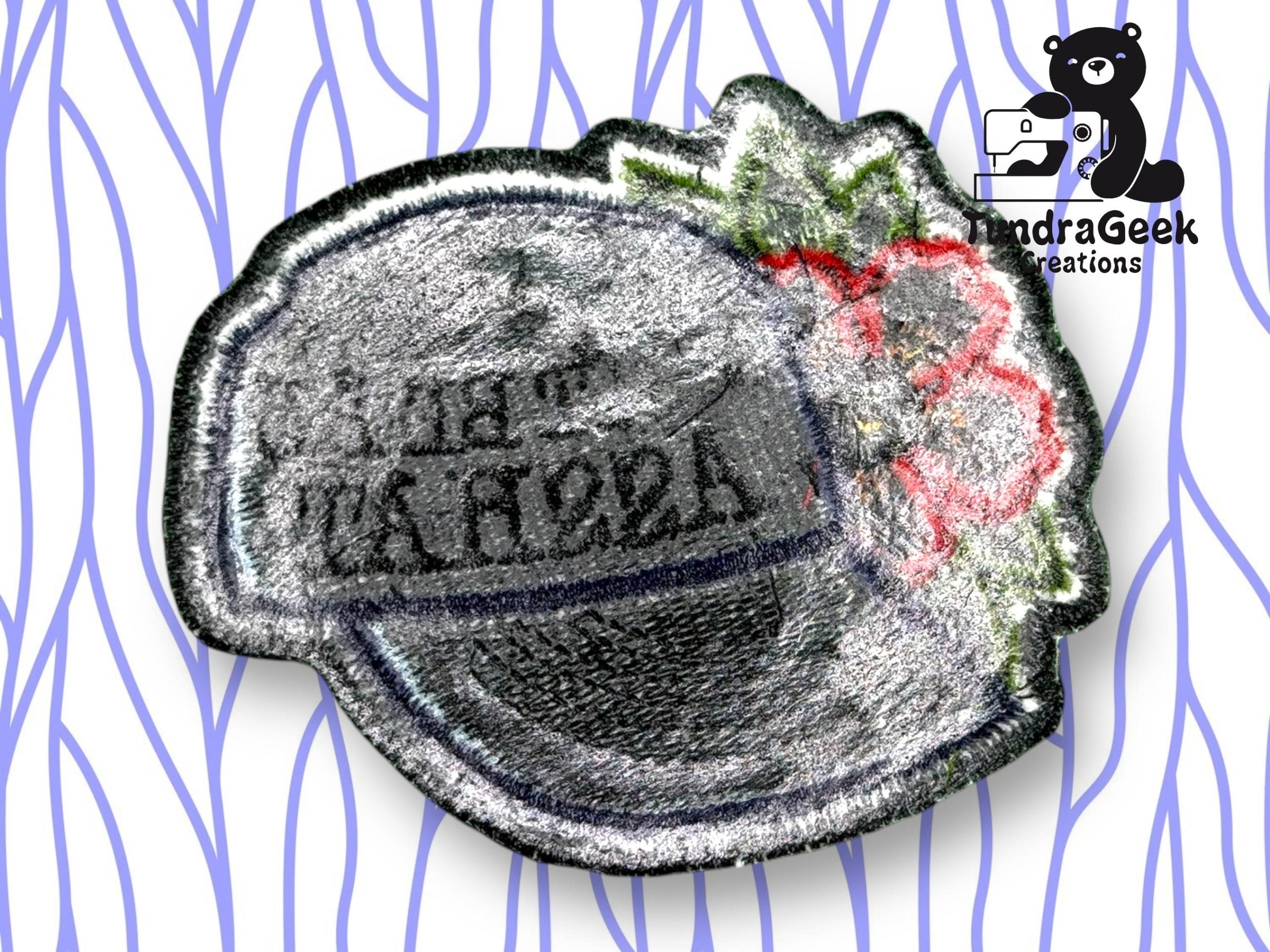 An embroidered patch with a gray circular design, red flower, and green leaves, shown with the reverse side facing up. A bear logo and PandraGeek Creations are in the top right corner.