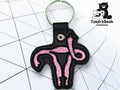 A black keychain with a pink embroidered uterus design sits on a white grid background; a bear logo with TundraGeek Creations is in the top right corner.