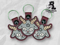 Three embroidered keychains featuring a gray goat head with yellow horns and a pentagram on its forehead, displayed on a geometric background with the TundraGeek Creations logo.