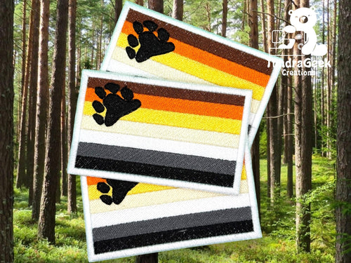 Three rectangular embroidered patches with bear paw prints and horizontal stripes in brown, orange, yellow, white, gray, and black are displayed against a forest background.