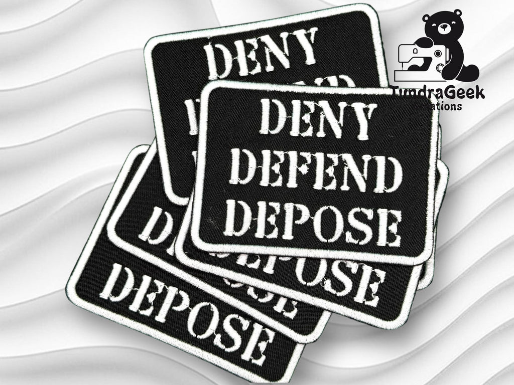 A stack of black rectangular patches with white text reading DENY DEFEND DEPOSE next to the TundraGeek Creations logo featuring a bear with a sewing machine.