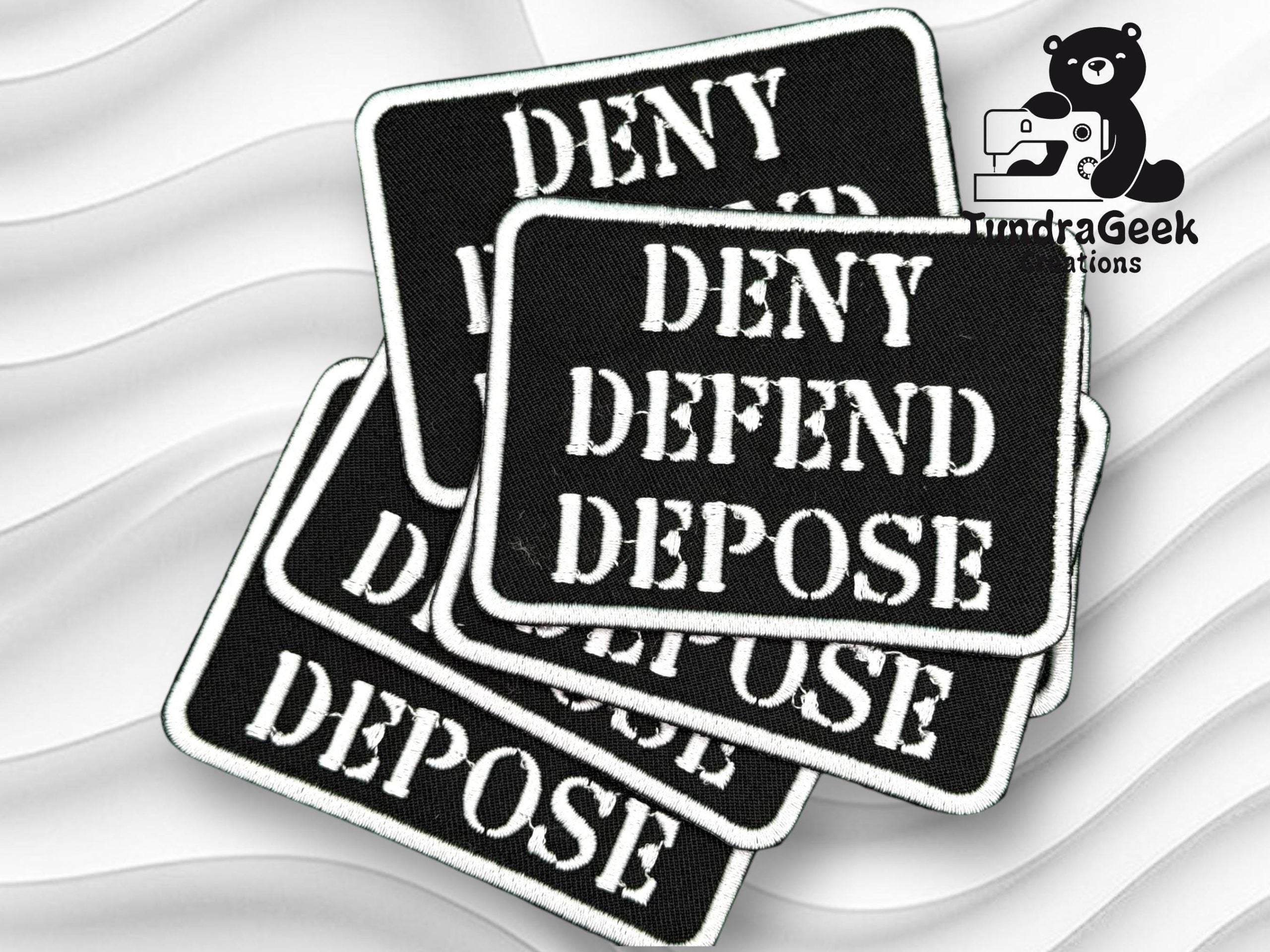 A stack of black rectangular patches with white text reading DENY DEFEND DEPOSE next to the TundraGeek Creations logo featuring a bear with a sewing machine.