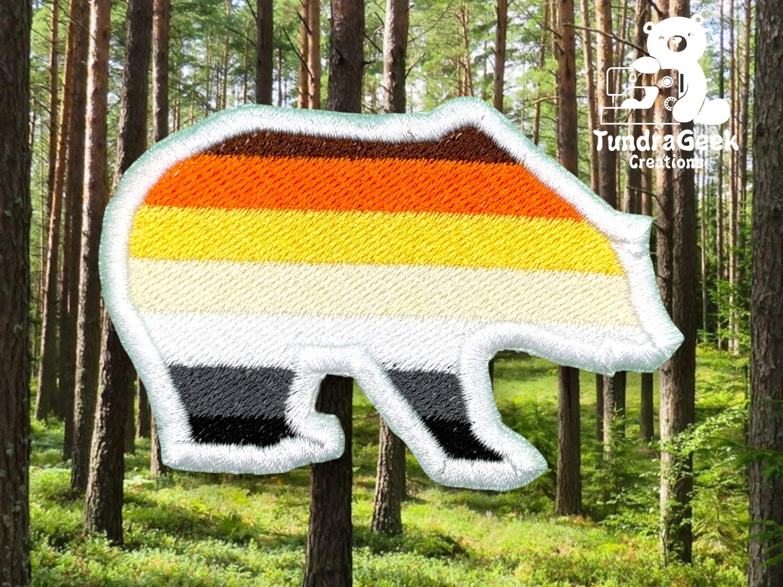 A bear-shaped patch with horizontal stripes in brown, orange, yellow, white, and black is placed over a forest background. Logo and text Tundra Geek Creations appear in the top right corner.