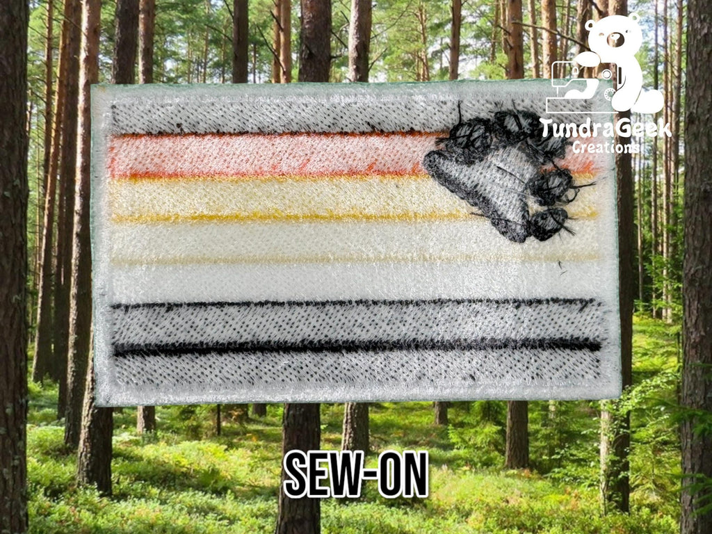Rectangular sew-on patch with horizontal stripes in orange, yellow, white, gray, and black, plus an embroidered porcupine, displayed in a forest setting.