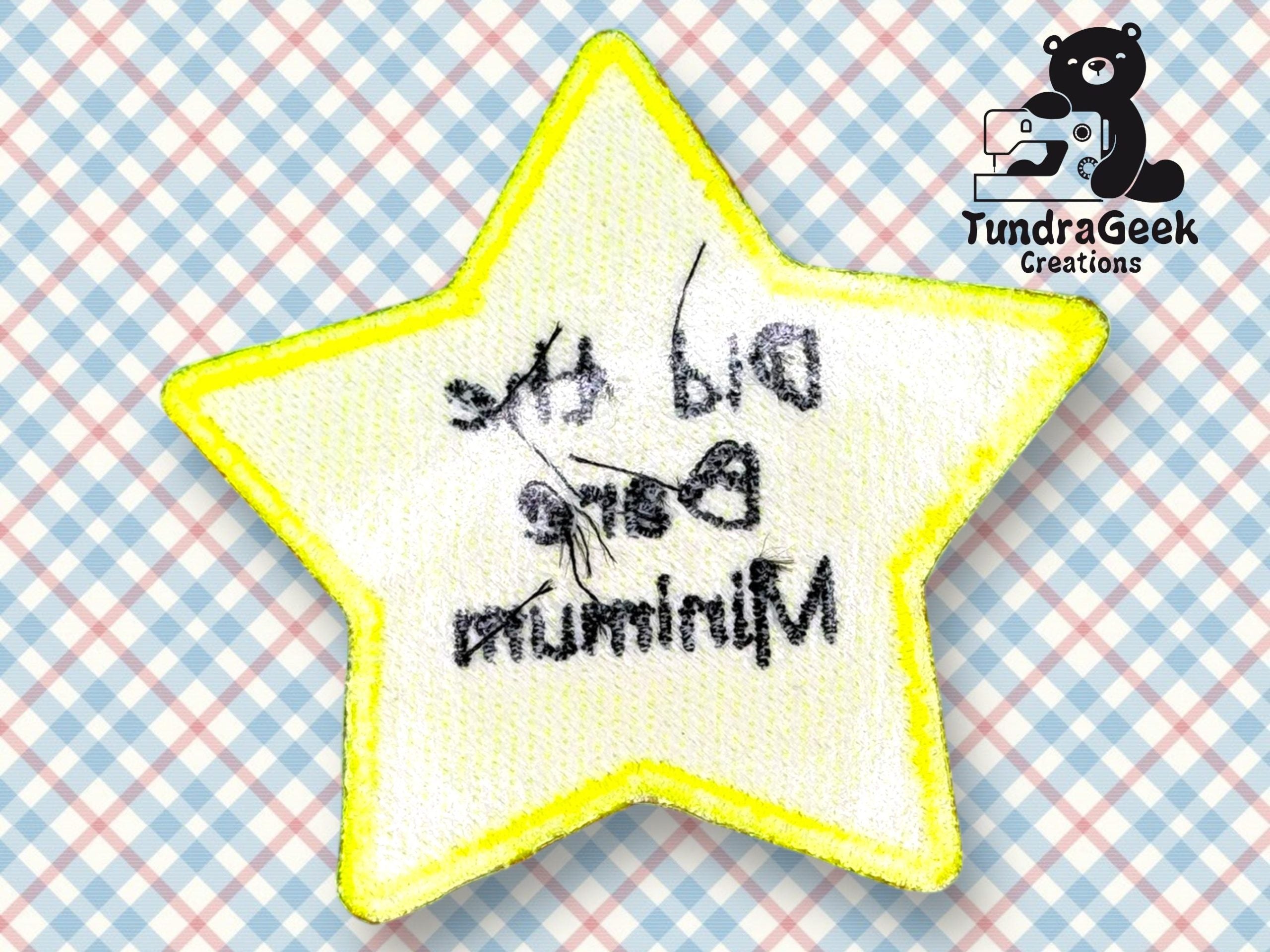 A yellow-edged star-shaped patch with backward text that reads, Did the bare minimum, on a pastel plaid background with a TundraGeek Creations logo in the corner.