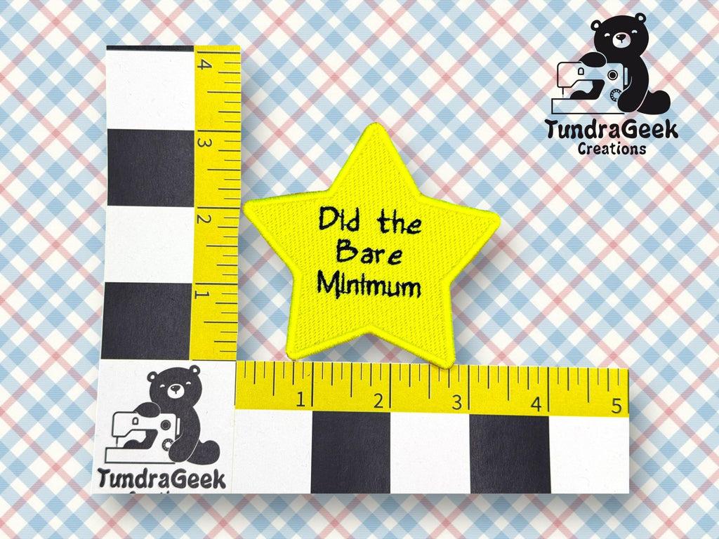 A yellow star-shaped patch with the text Did the Bare Minimum is placed on a measurement grid showing it is about 3 inches wide. TundraGeek Creations logo is visible.