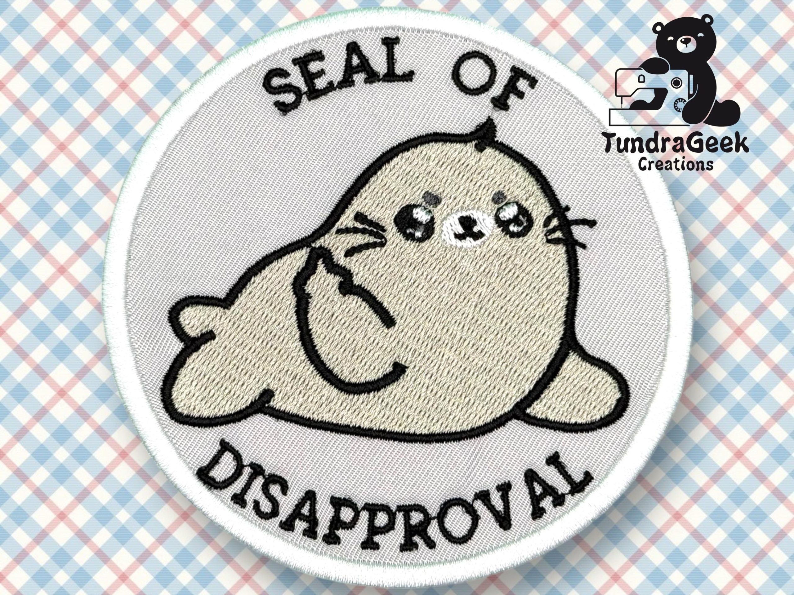 An embroidered patch shows a cartoon seal giving a middle finger, with the text SEAL OF DISAPPROVAL above and below the seal.