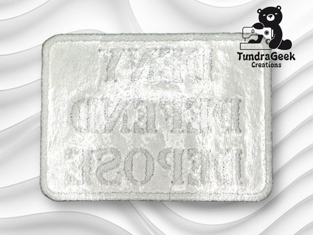 A rectangular embroidered patch with mirrored text on a white background, featuring the TundraGeek Creations logo with a bear holding a sewing machine in the top right corner.