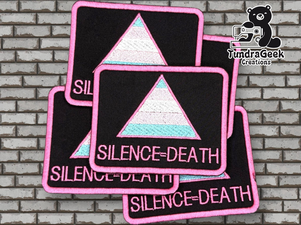 Four rectangular patches with a pastel-colored triangle and the text SILENCE = DEATH are displayed on a brick background, with the TundraGeek Creations logo in the upper right corner.