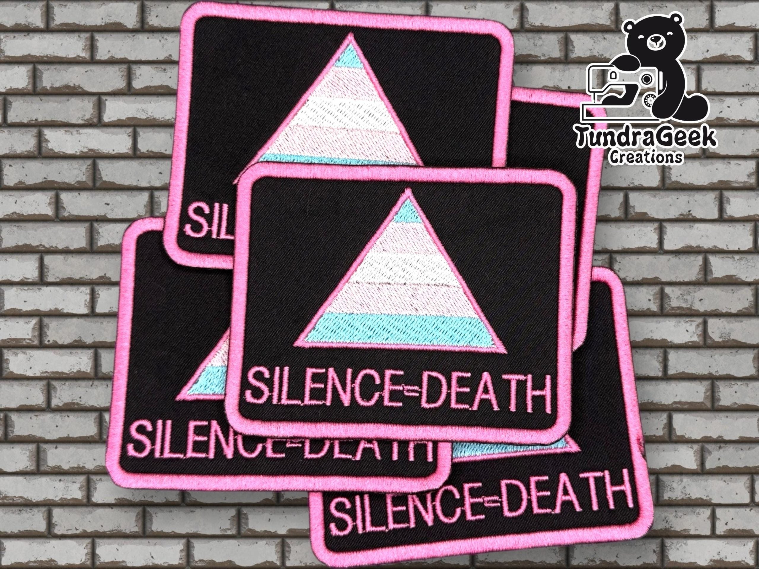 Four rectangular patches with a pastel-colored triangle and the text SILENCE = DEATH are displayed on a brick background, with the TundraGeek Creations logo in the upper right corner.