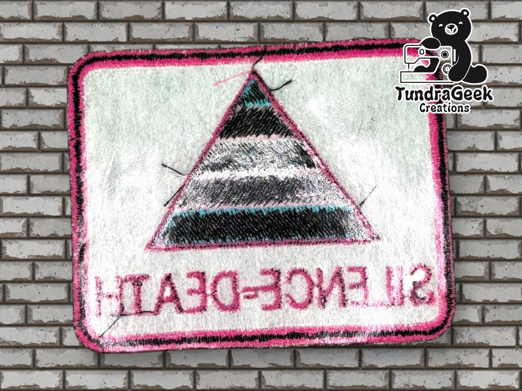 A rectangular embroidered patch with a striped triangle and the text “SILENCE = DEATH” in reverse, displayed on a brick wall with a TundraGeek Creations logo in the corner.
