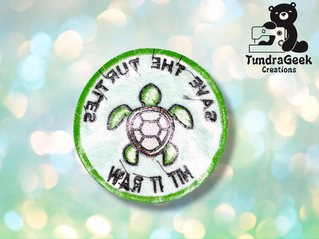 A round embroidered patch with a turtle illustration and the words SAVE THE TURTLES HIT IT RAW stitched around it; TundraGeek Creations logo in the top right corner.