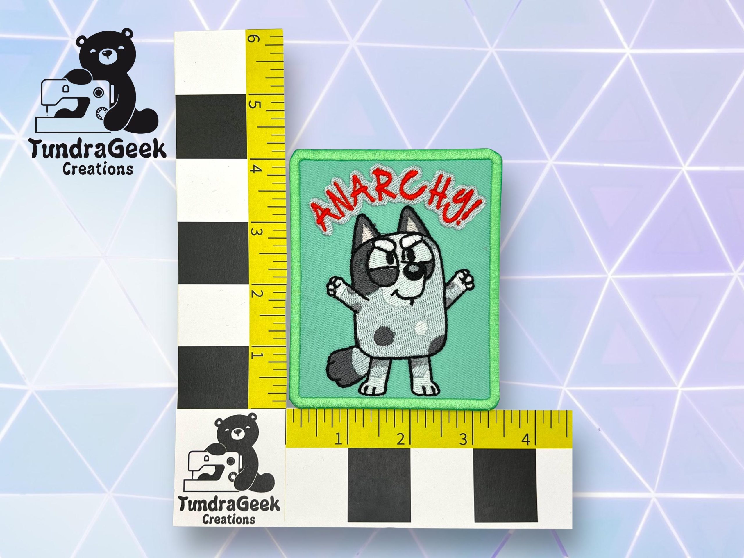 A rectangular embroidered patch with a cartoon dog, raised fist, and the word ANARCHY!! in red, shown with a measurement grid from TundraGeek Creations. Patch measures about 3x3 inches.