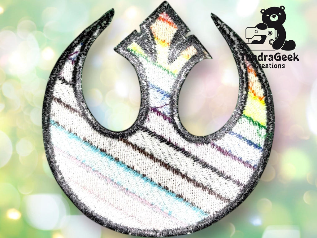 Embroidered patch of the Star Wars Rebel Alliance symbol with rainbow stitching, displayed on a blurred, pastel background, with the PandraGeek Creations logo in the top right corner.