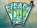 Three identical patches show a cartoon frog pointing upward with the text, I may have a touch of the tism. Background has a blue and green textured pattern.