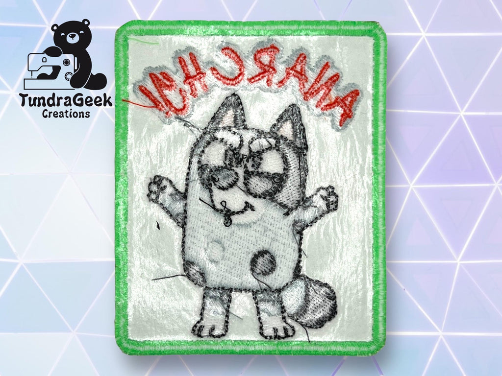 Embroidered patch with a cartoon cat and the word ANARCHY stitched in red, upside down. Logo for TundraGeek Creations and a sewing bear icon appear in the background.