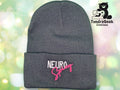 A gray knit beanie with the words NEURO Spicy embroidered in white and pink. The TundraGeek Creations logo with a bear and sewing machine is in the top right corner.