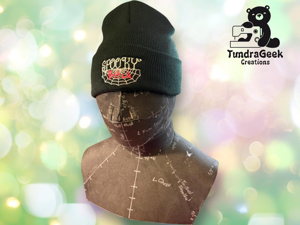A mannequin head displays a black beanie with SPOOKY and red fangs embroidered on it; TundraGeek Creations logo appears in the top right corner.