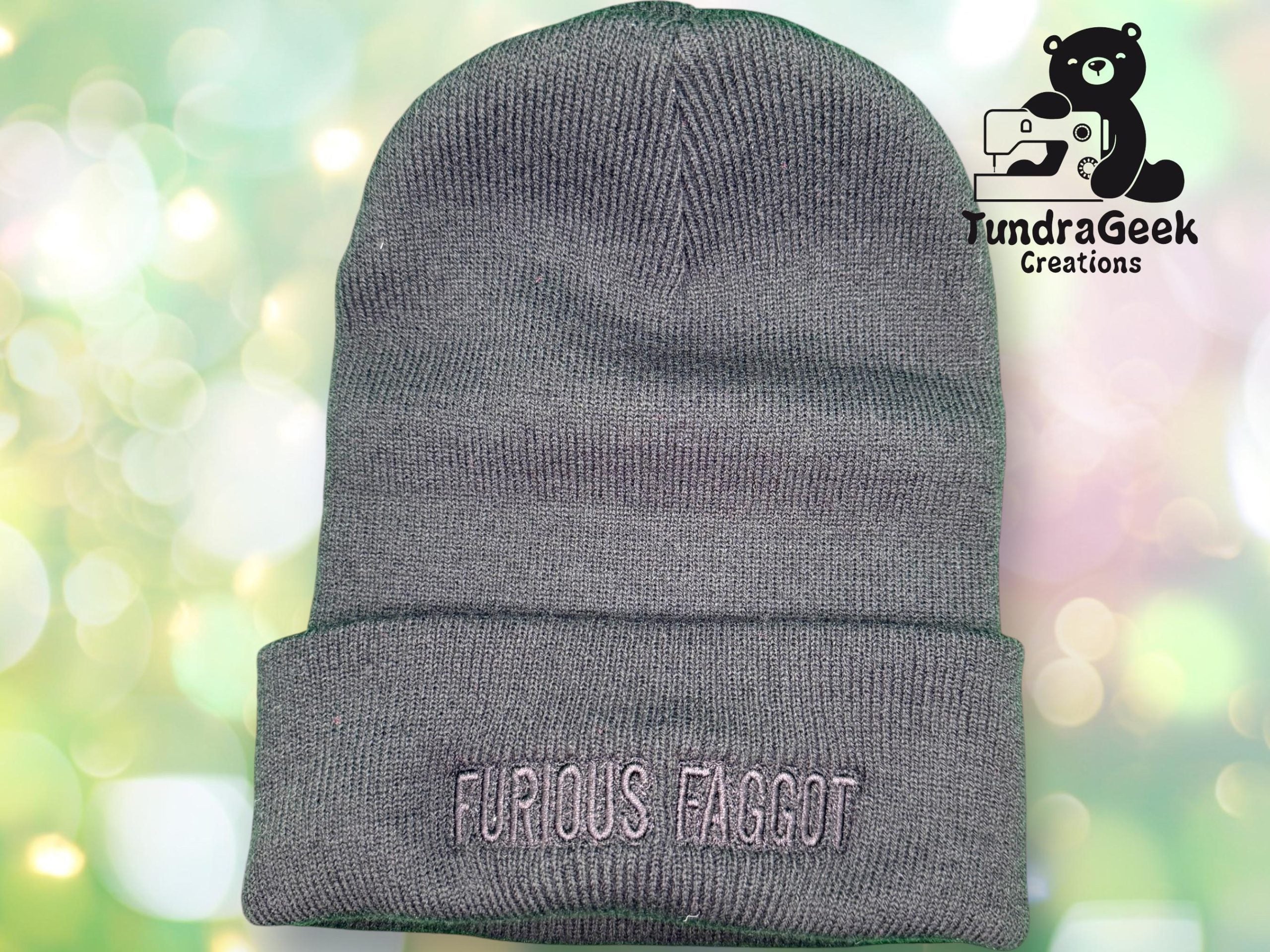 A gray knit beanie with FURIOUS FAGGOT embroidered on the folded brim; a TundraGeek Creations logo is visible in the top right corner.