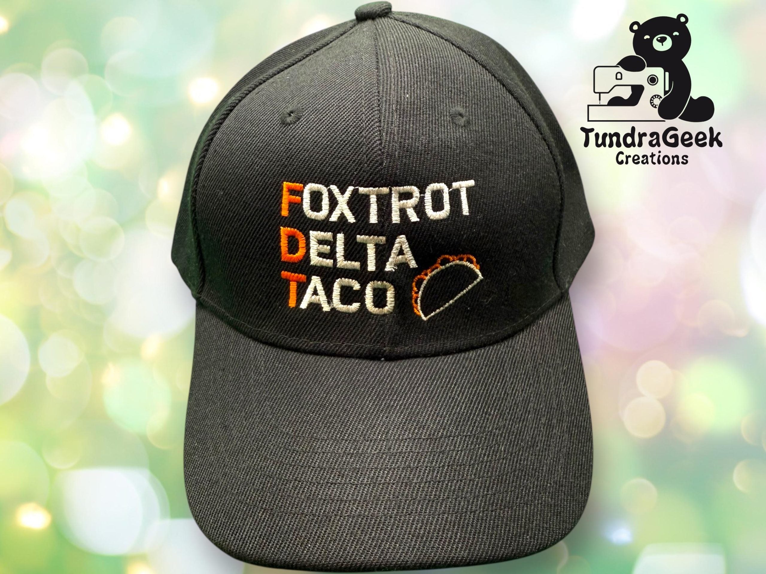 A black baseball cap with Foxtrot Delta Taco and a taco image embroidered on the front. TundraGeek Creations logo in the top right corner.