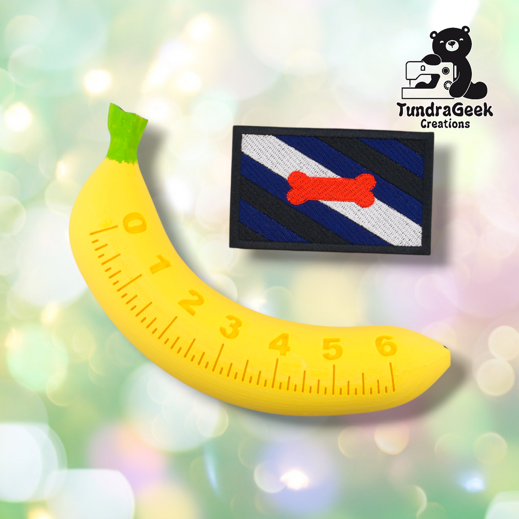 A yellow banana-shaped ruler (0–6) is beside the Pup Pride Flag Patch by TundraGeek Creations, a rectangular embroidered patch with diagonal blue, black, and white stripes plus a red bone. Logo appears in the corner.