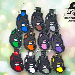Black vinyl keychains with a pup hood design embroidered on them in various colors